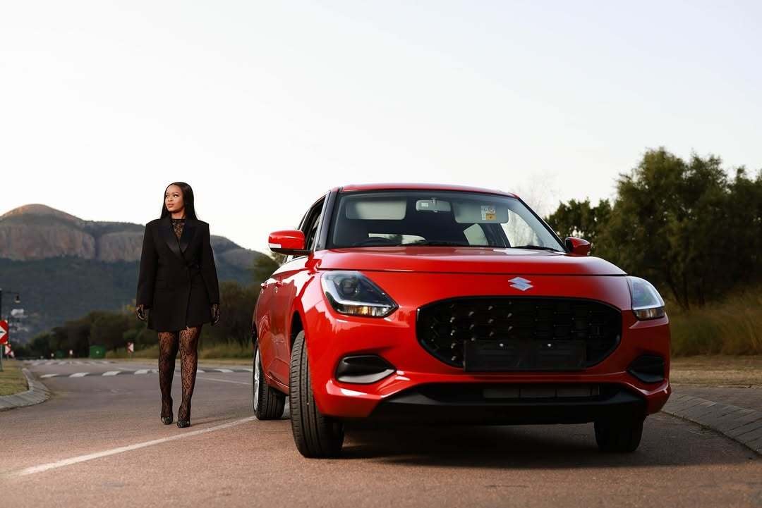 A woman walking next to a suzuki car