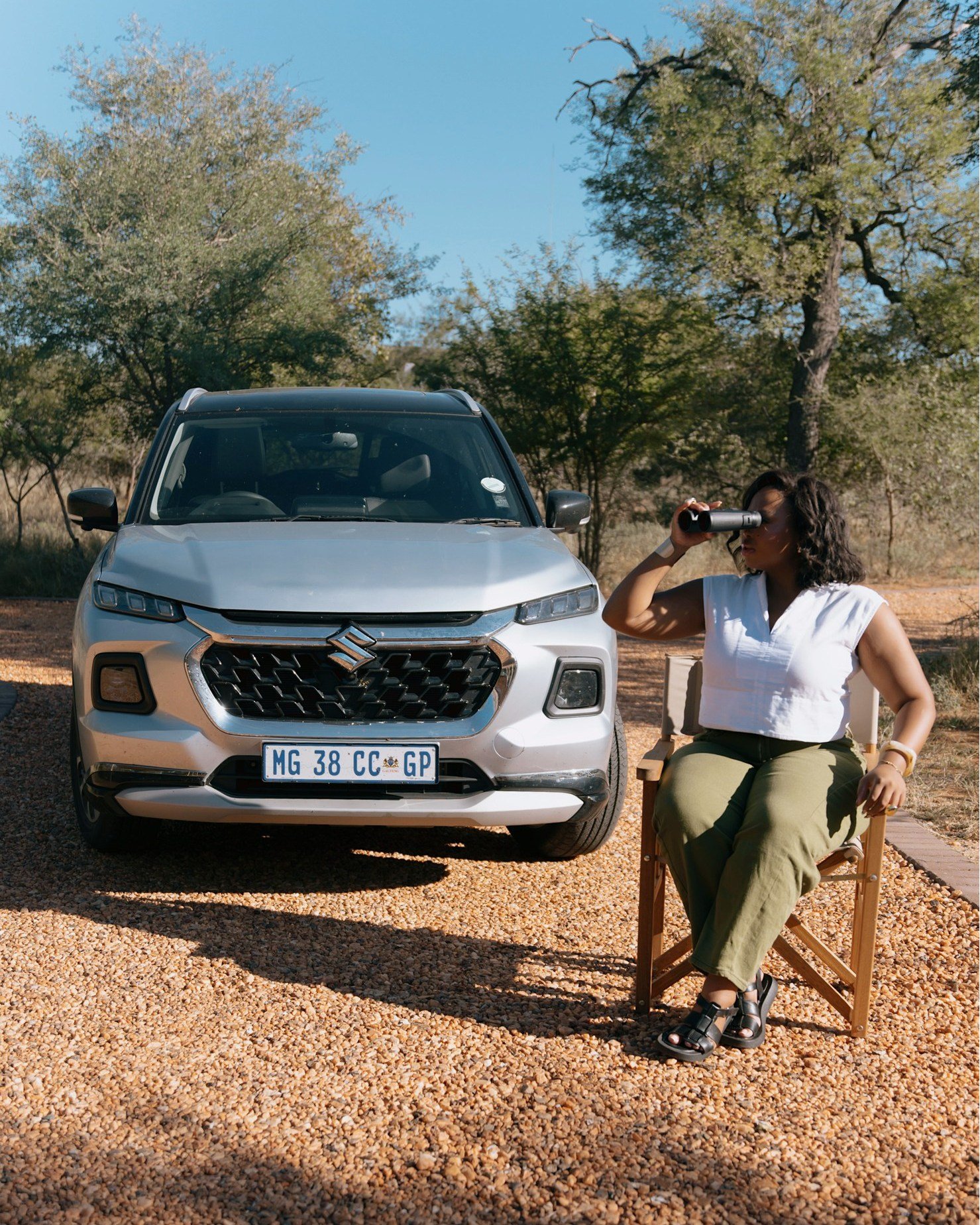 Lady with binoculars next to a suzuki car